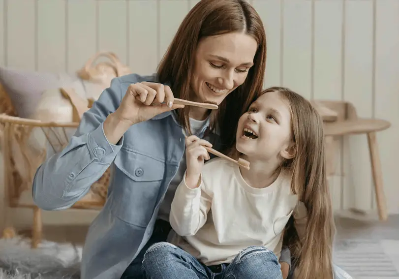 mom and daughter smiling and holding toothbrushes